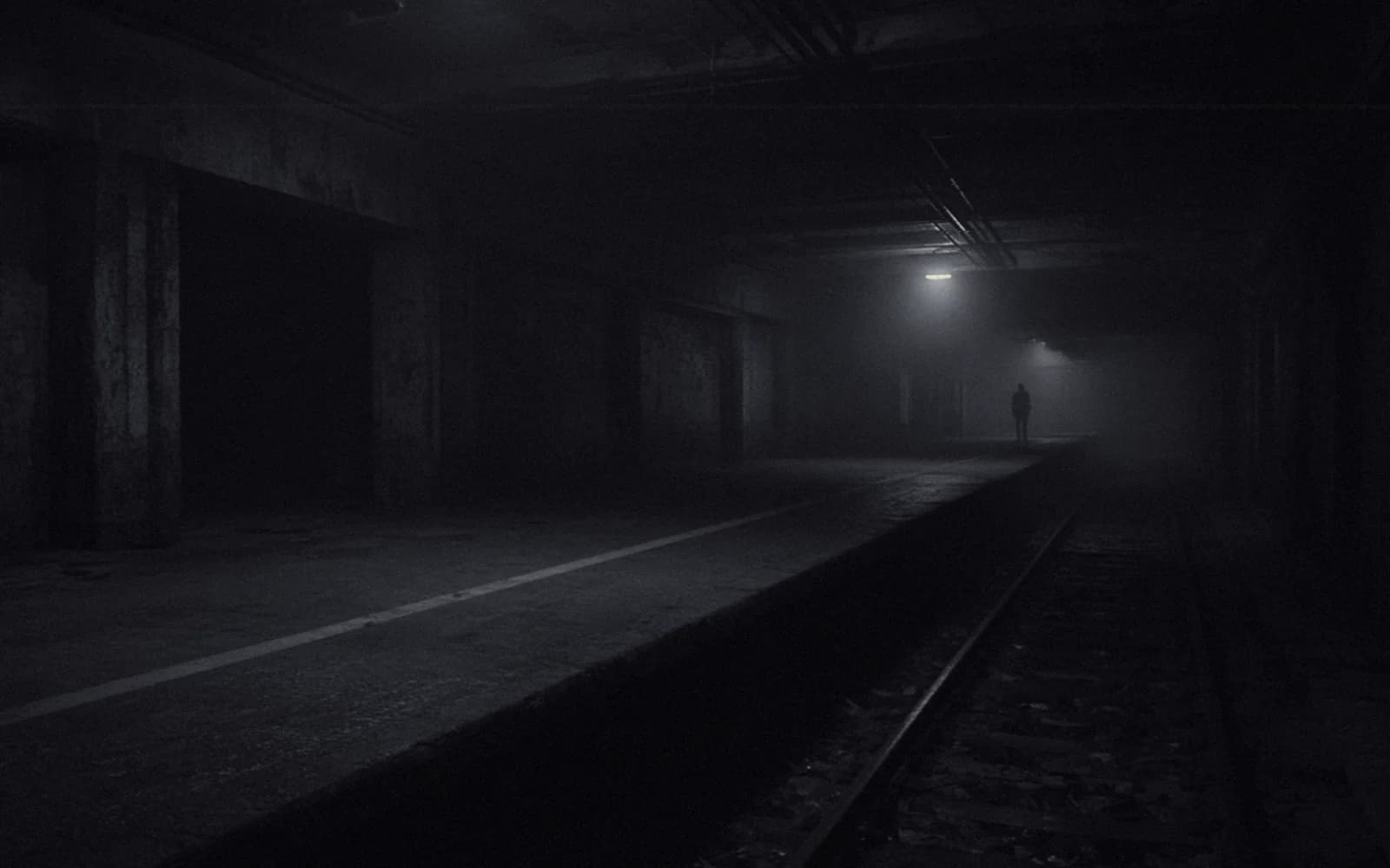 Dark silhouette of an ordinary human figure standing far down an empty station platform, labeled planned.